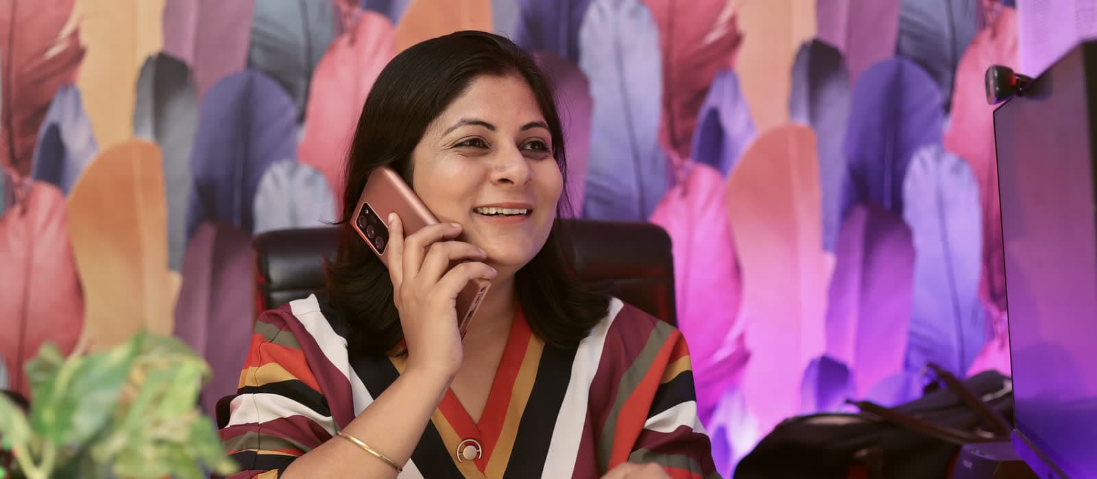 A woman smiling on a phone call at her desk