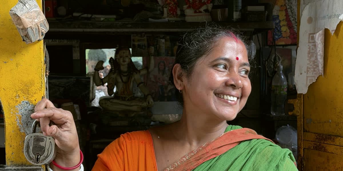 A shopkeeper smiling at her shop doorway