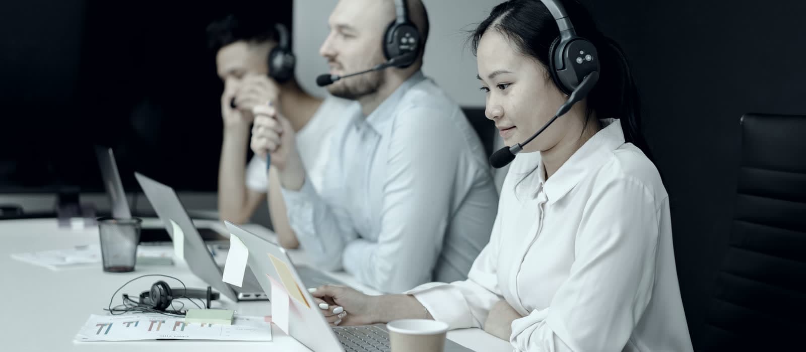 Support agents in headsets working at their laptops