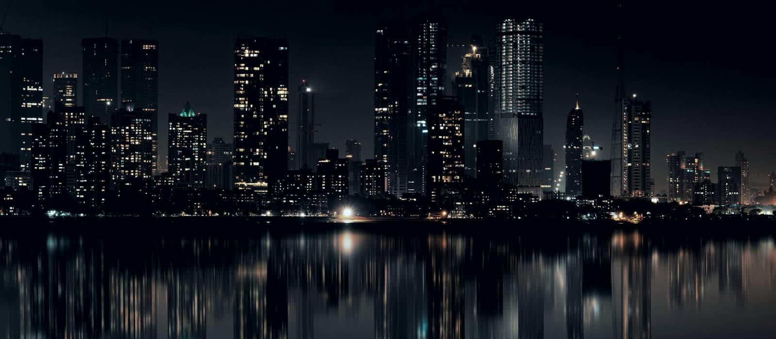 A city skyline lit up at night over still water