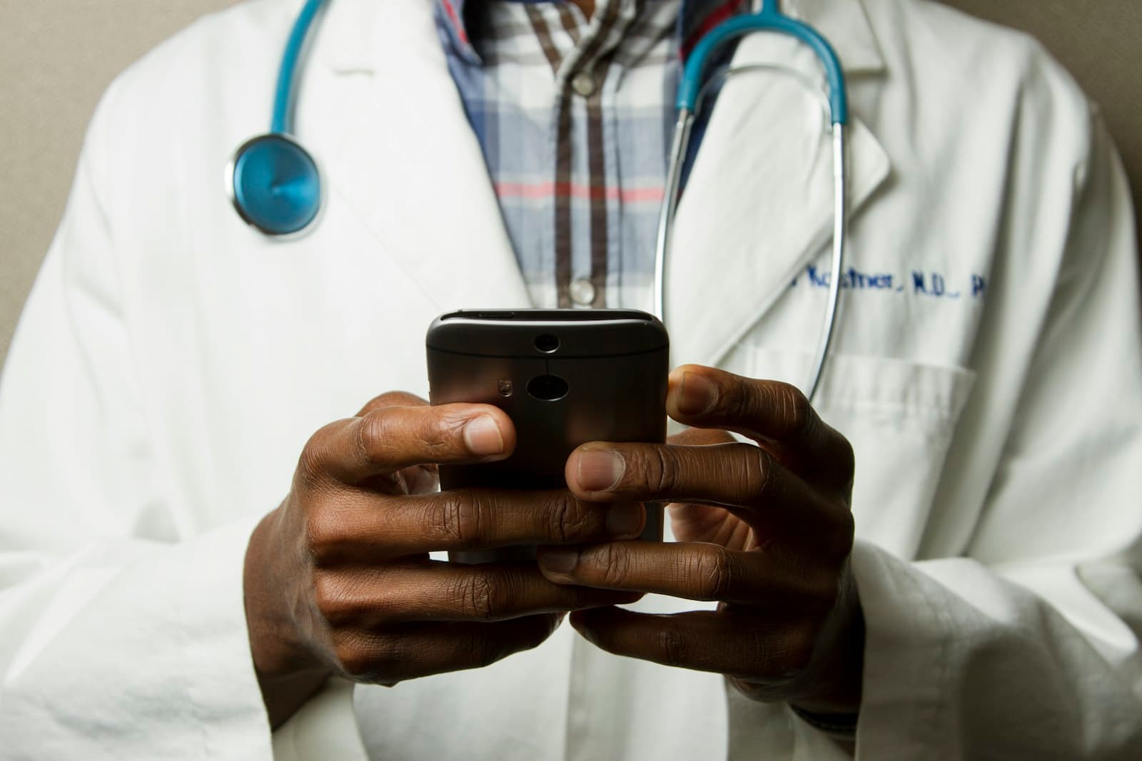 A clinician in a white coat holding a phone