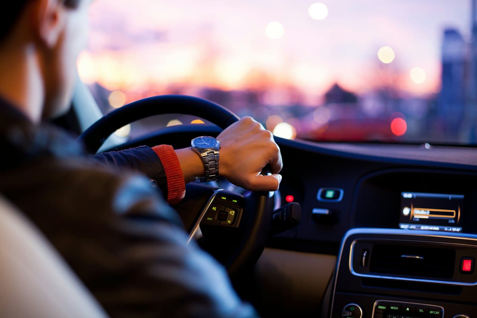 A driver's hand steady on the wheel at dusk