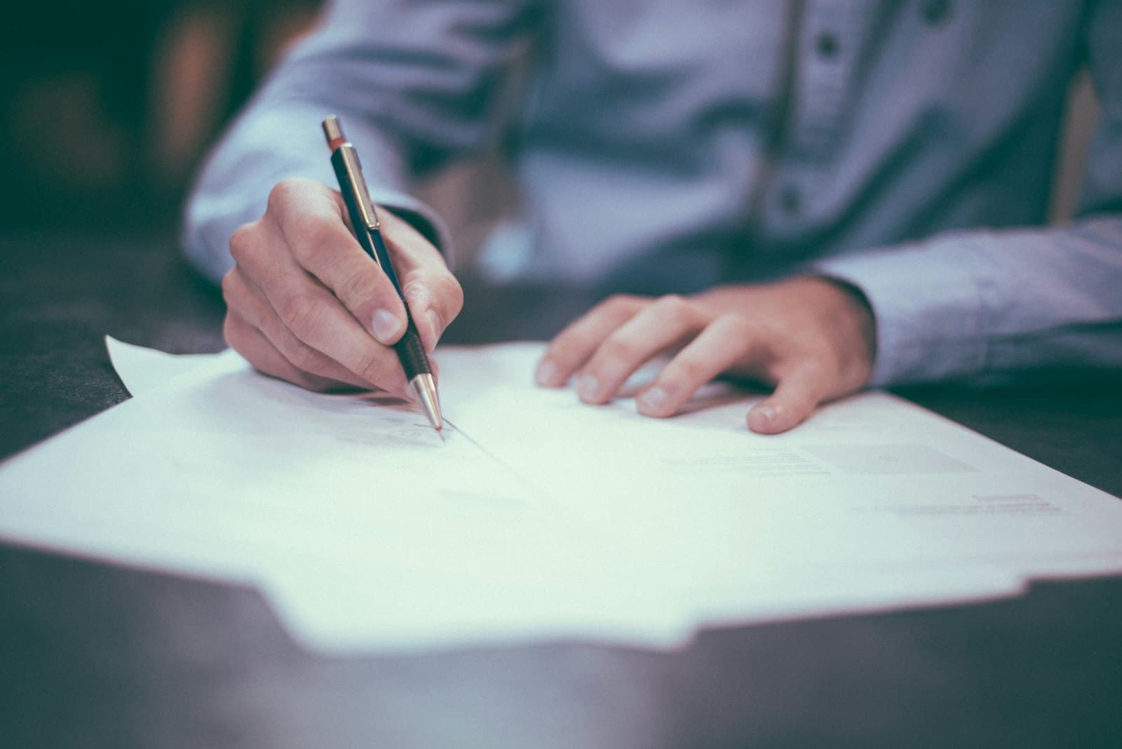 A person signing a document at a desk
