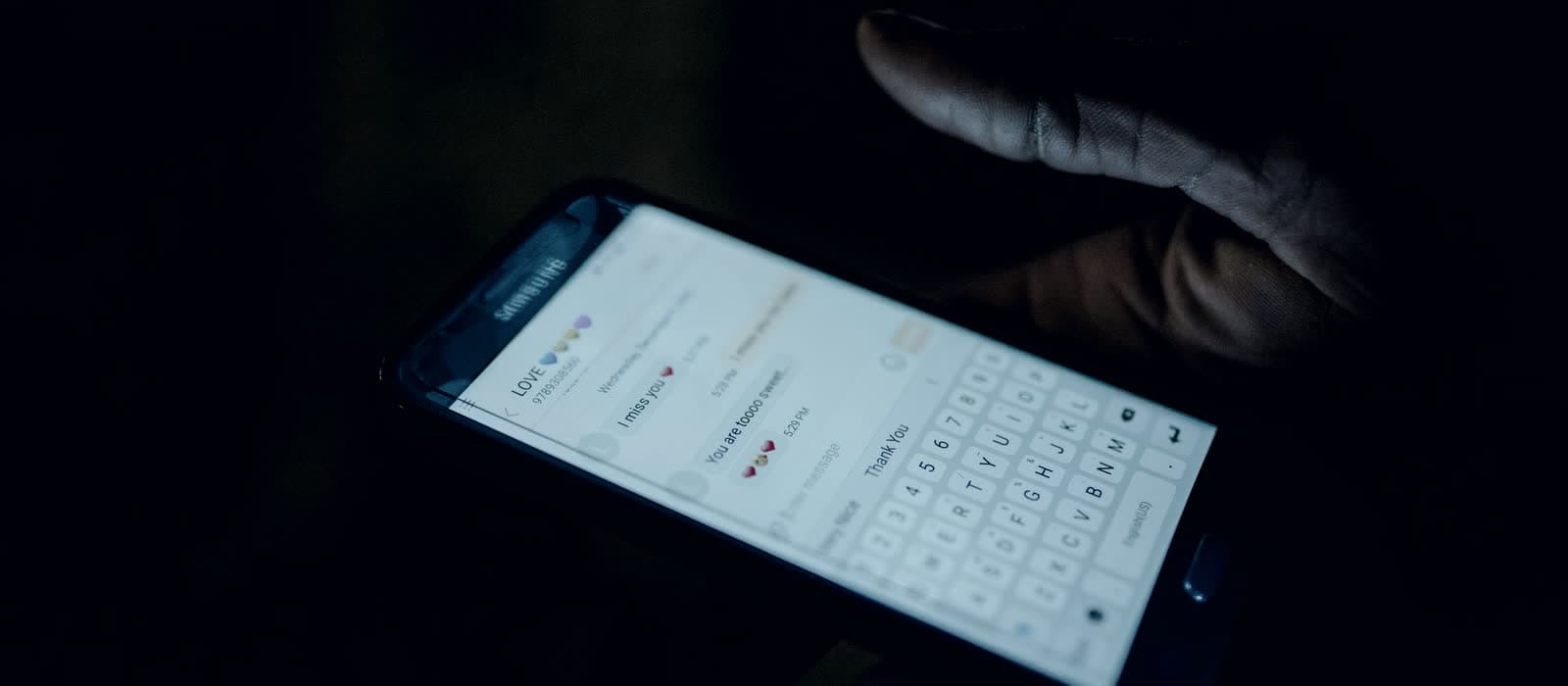 A hand holding a phone with a messaging app open