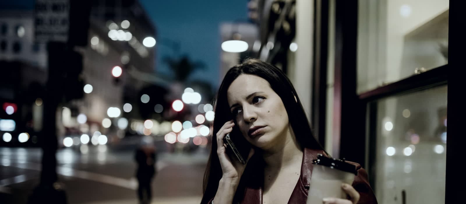 A woman taking a phone call on a city street at night
